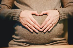Femme enceinte tenant son ventre en forme de coeur - bébé entend le bola de grossesse
