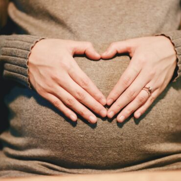 Femme enceinte tenant son ventre en forme de coeur - bébé entend le bola de grossesse
