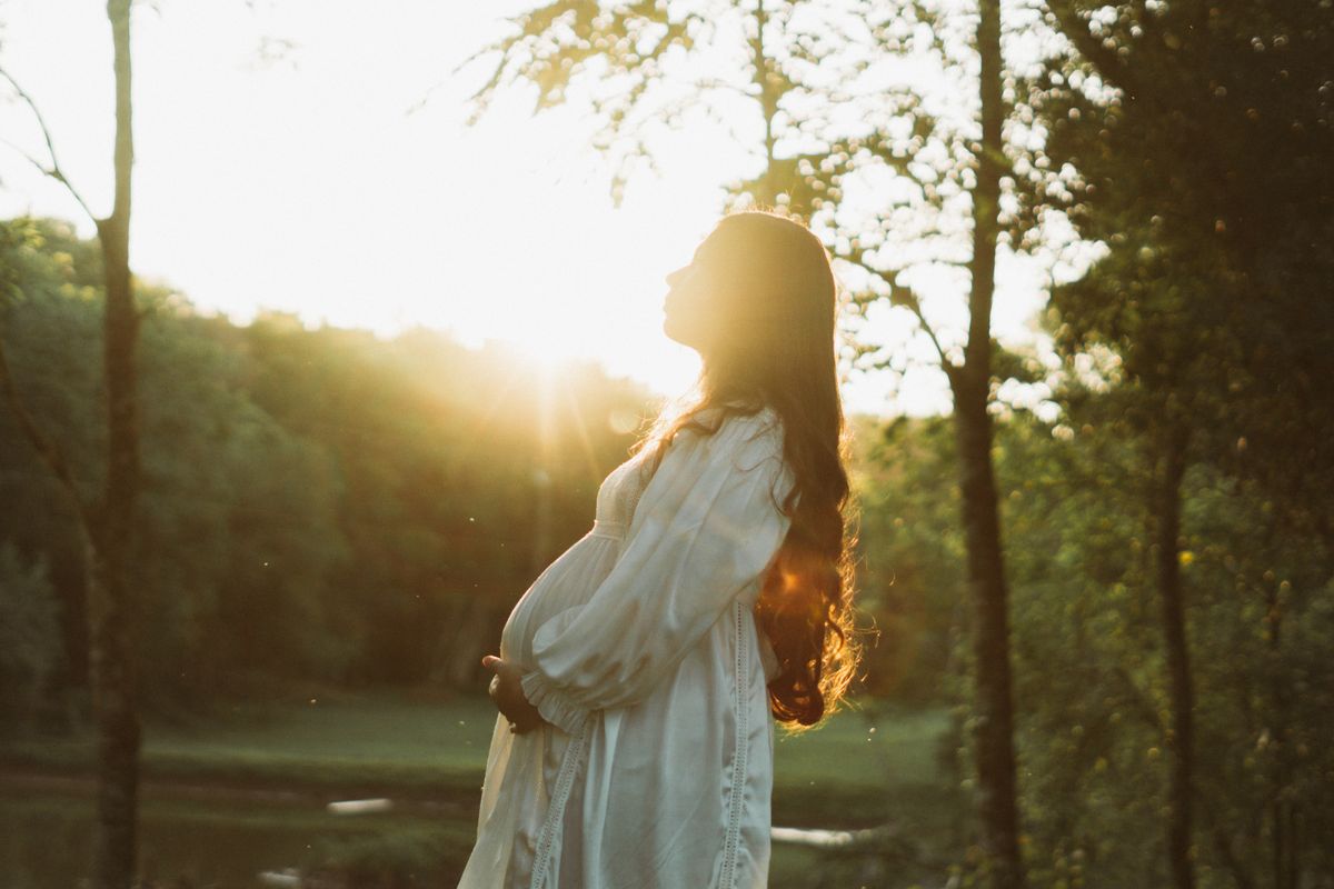 Femme enceinte sereine portant un bola de grossesse au coucher du soleil